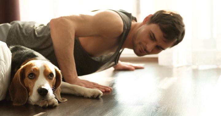 A man working out at home during COVID-19 with his dog.