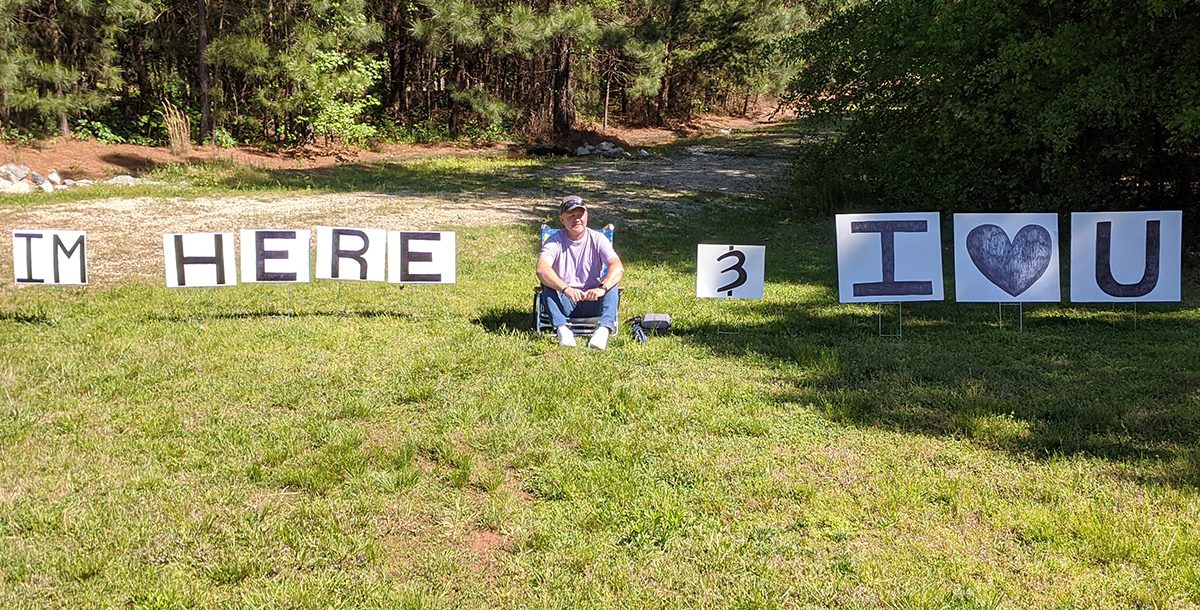 Dennis sitting outside Bon Secours St. Francis Cancer Center with his signs for Diana.