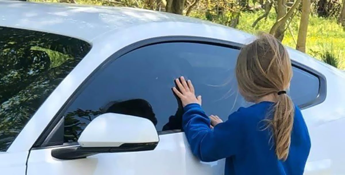 Carly and Briggs having a social distance visit during COVID-19 using a car window.