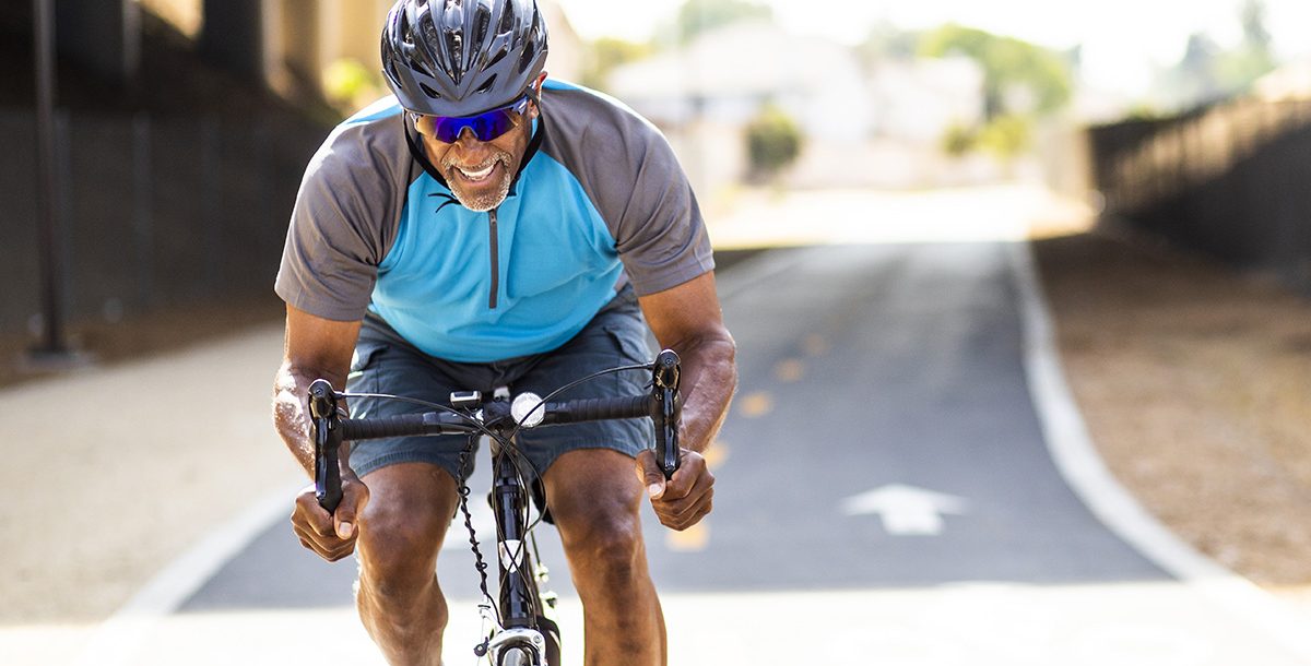 A man working out by cycling outside during the summer months