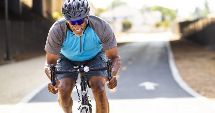 A man working out by cycling outside during the summer months