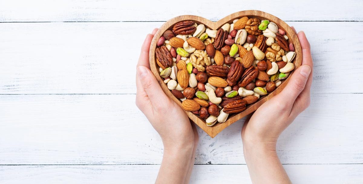 A photo of heart healthy nuts in a heart-shaped bowl.