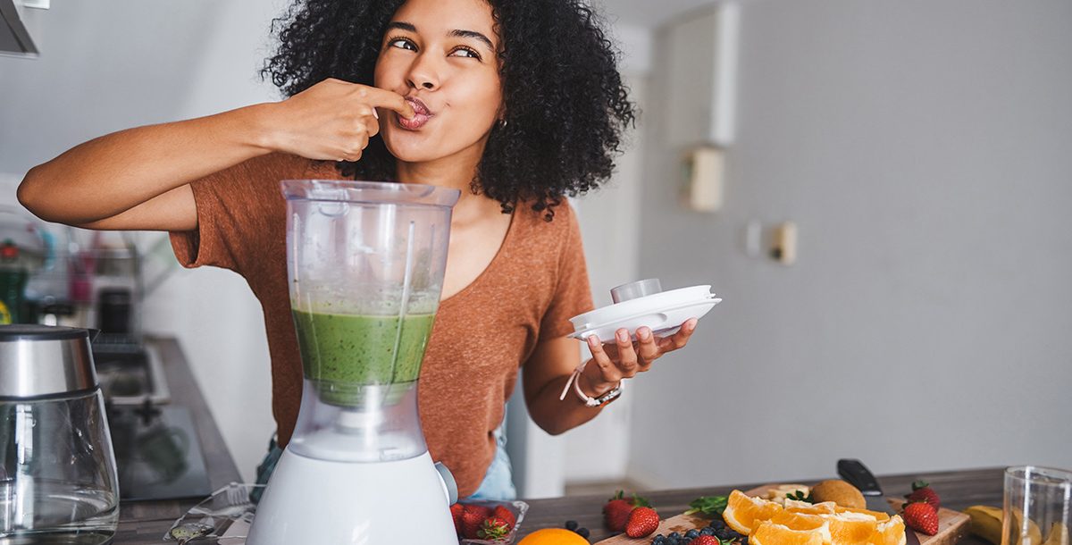 A woman making a healthy smoothie in her kitchen.