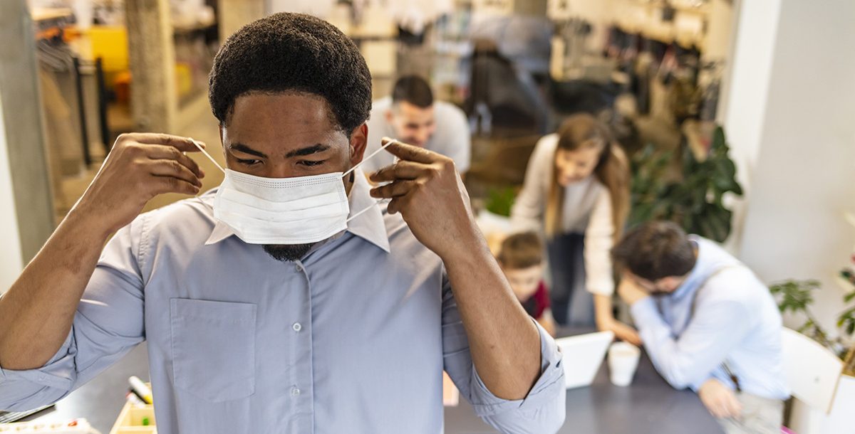 A man putting on a mask around others to protect himself from COVID-19.