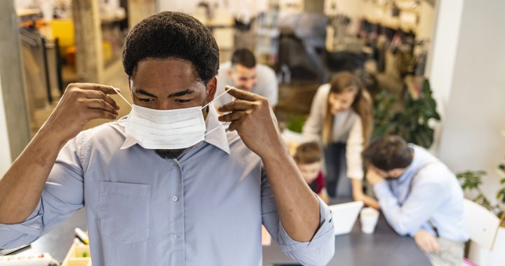 A man putting on a mask around others to protect himself from COVID-19.