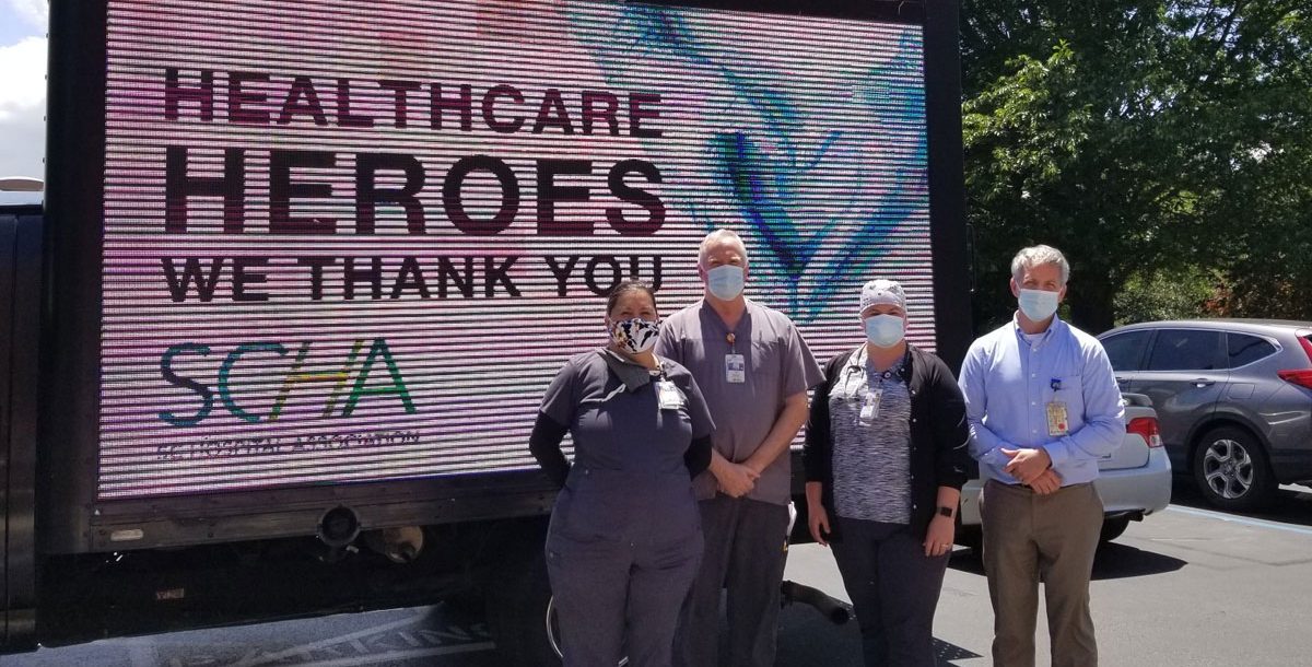 A group of Bon Secours respiratory therapists outside by a health care heroes sign