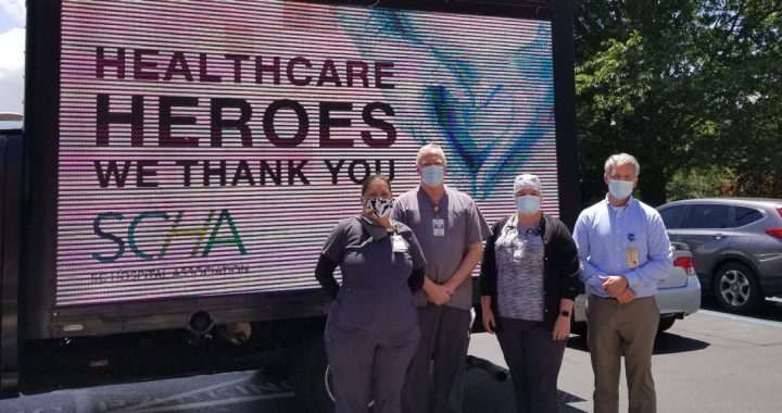 A group of Bon Secours respiratory therapists outside by a health care heroes sign