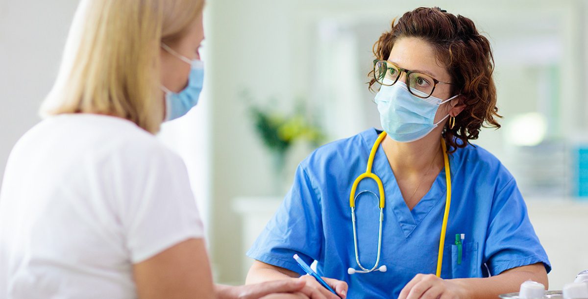 A medical provider caring for a patient while wearing a face mask.