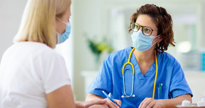 A medical provider caring for a patient while wearing a face mask.