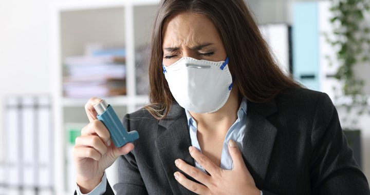 A woman suffering from asthma and using an inhaler.