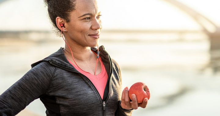 A woman eating an apple after exercising to help lower her cholesterol.