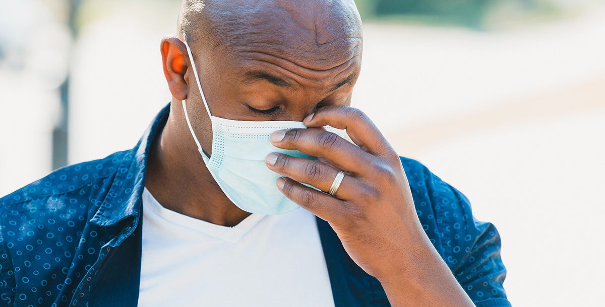 A man experiencing a headache while wearing a face mask.