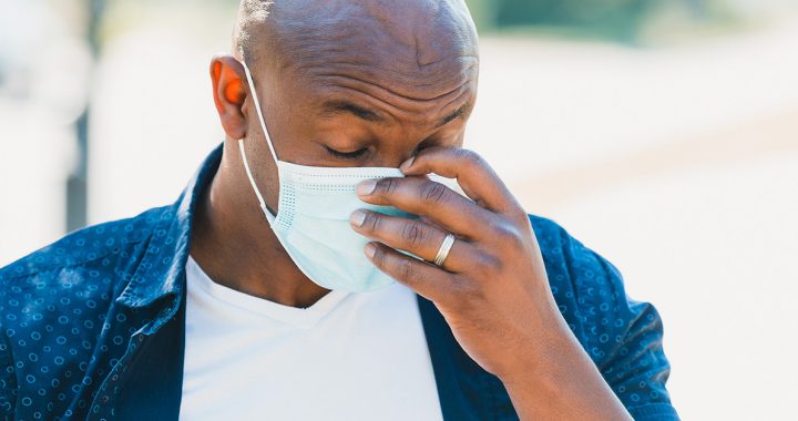 A man experiencing a headache while wearing a face mask.