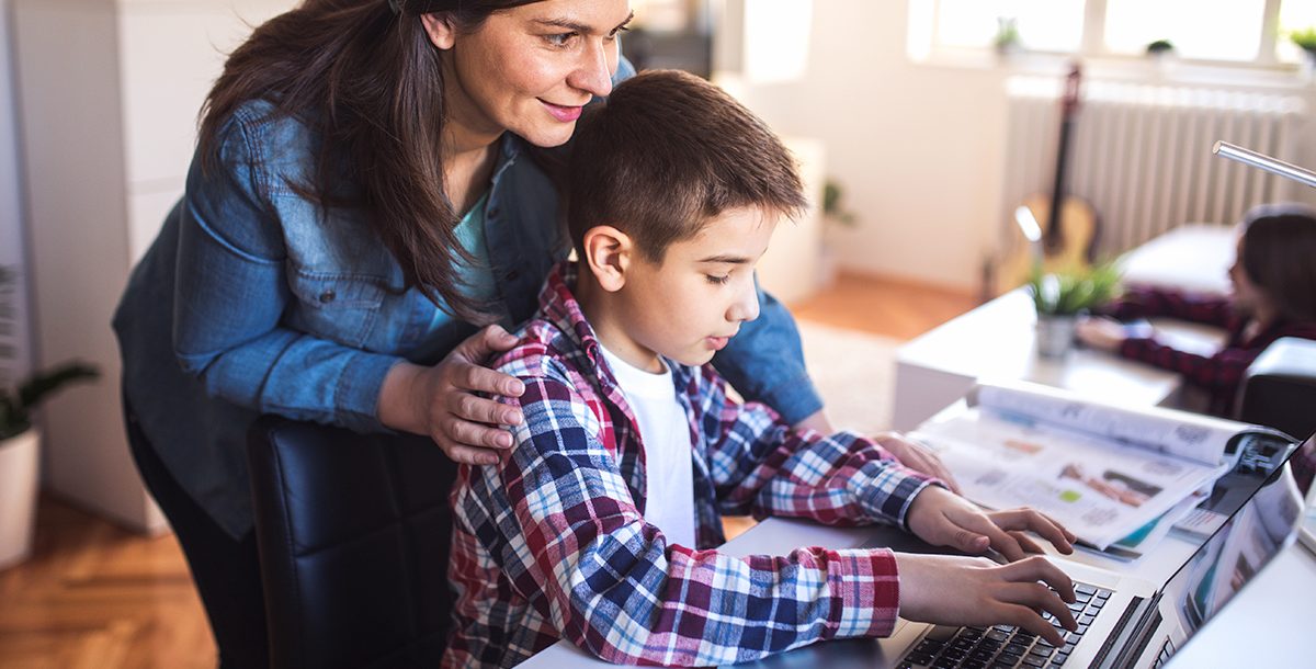 A mother helping her son with virtual learning at home during the back-to-school season.