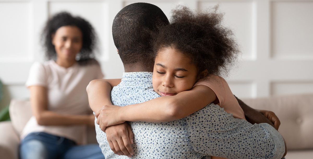 A father comforting his daughter with a hug during COVID-19.