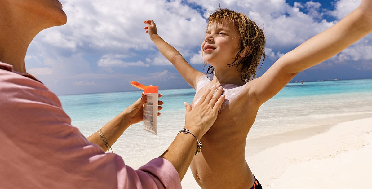 A parent applying sunscreen to their child.