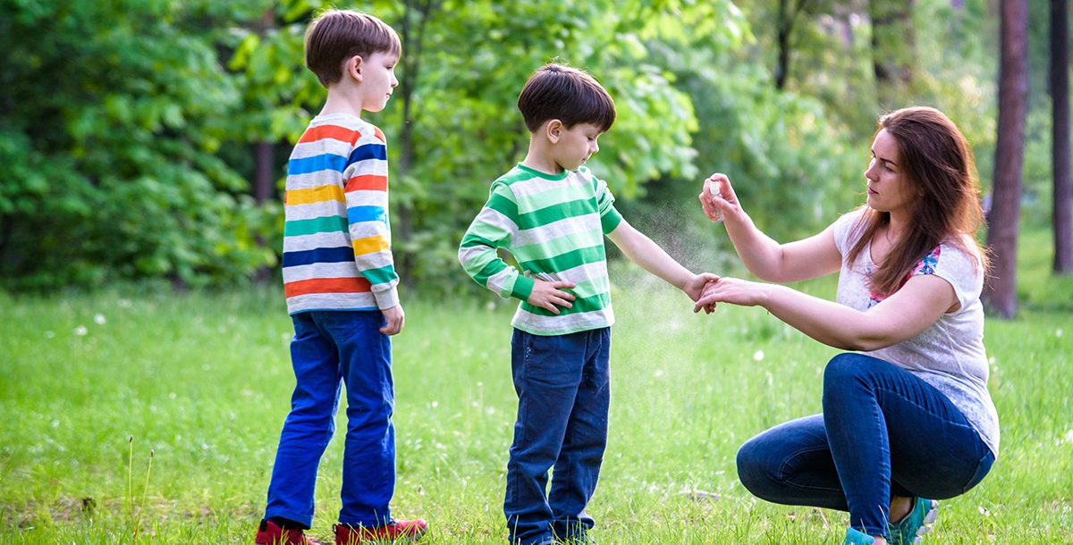 A mother spraying insect repellent on her kids.