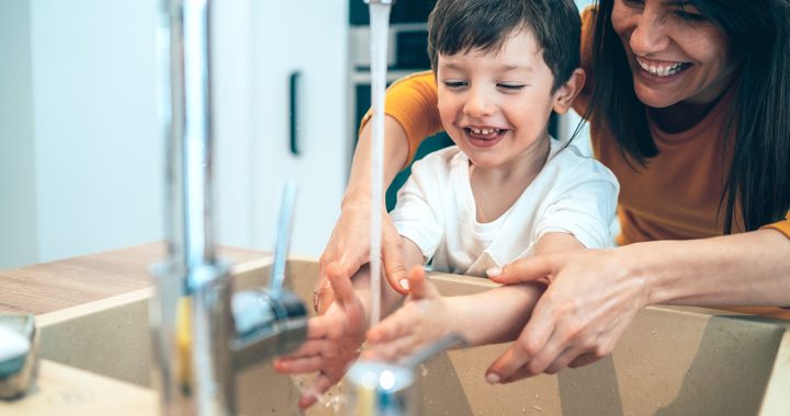 A mom helping her child was their hands.