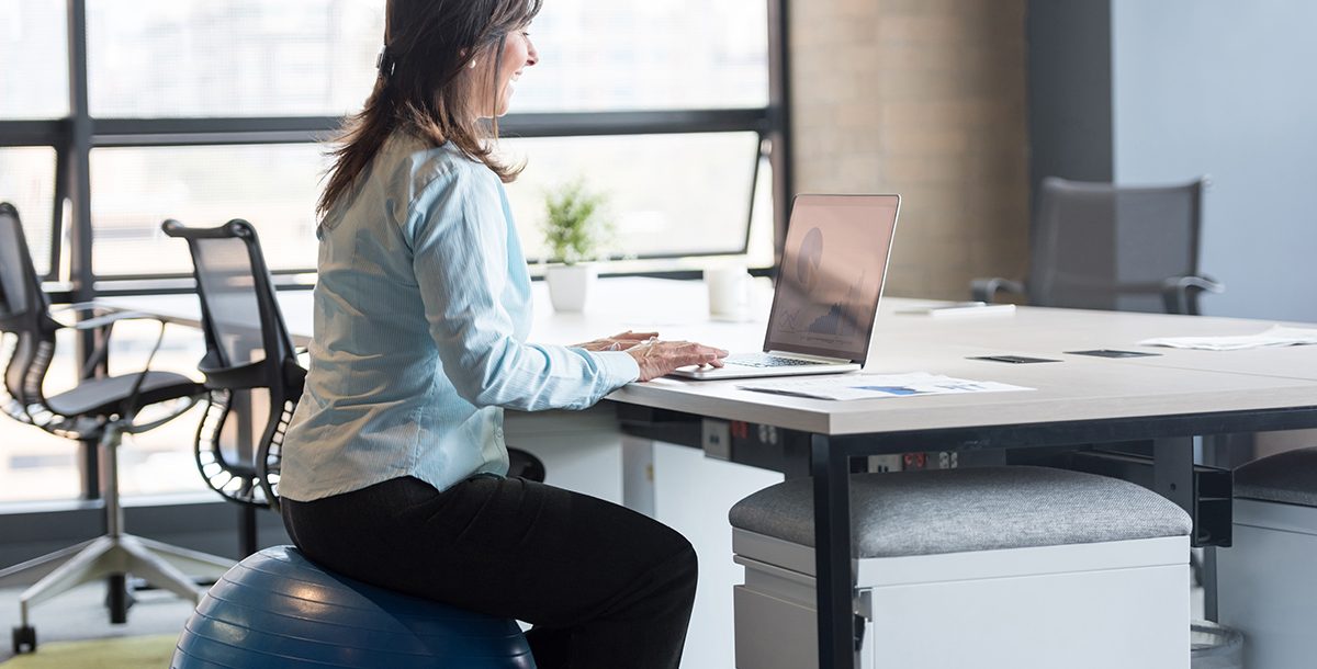 A woman using an exercise ball during work.