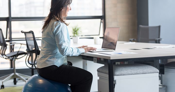 A woman using an exercise ball during work.